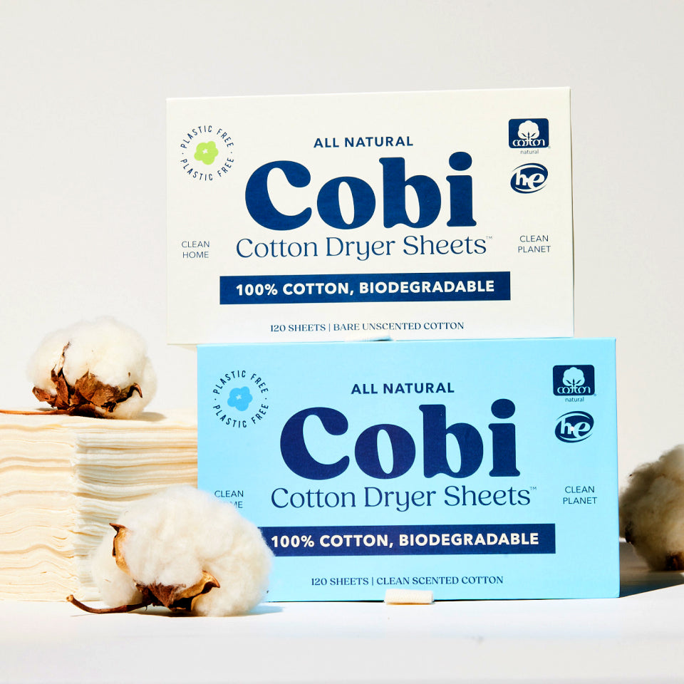 Two stacked boxes of Cobi dryer sheets next to Cobi dryer sheets and cotton sprigs